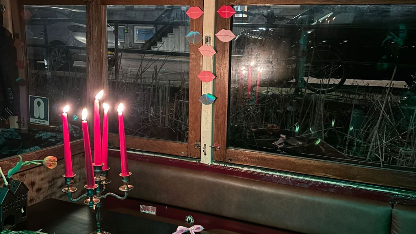 Boat interior with candles, flowers, and ribbons on a table.