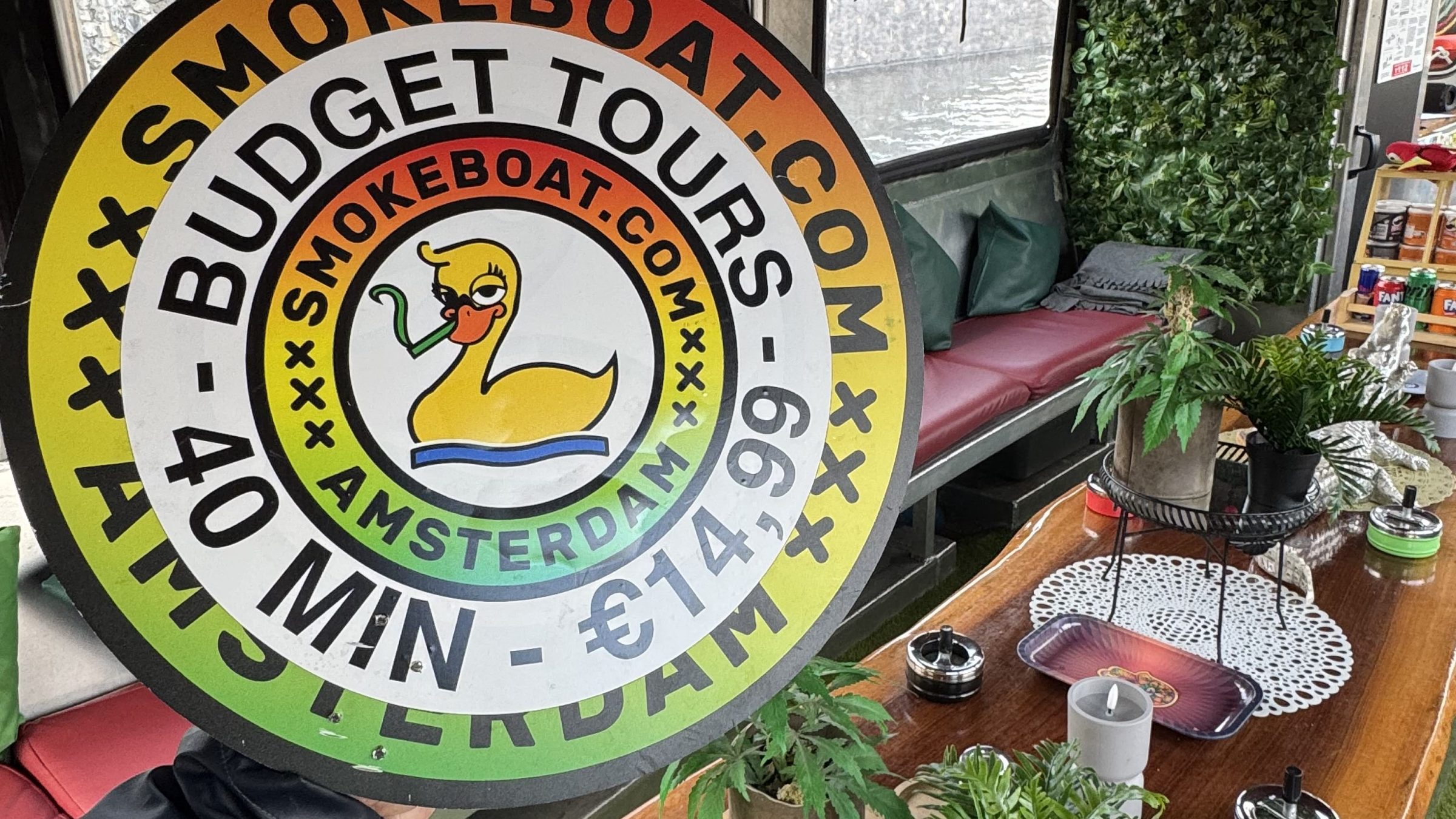 Interior of a decorated boat with greenery, round sign, and dining setup.