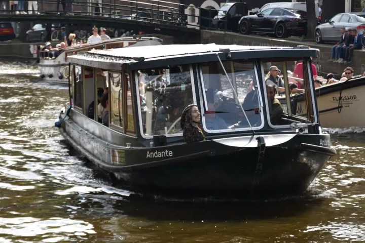 A boat navigates a canal with buildings in the background.
