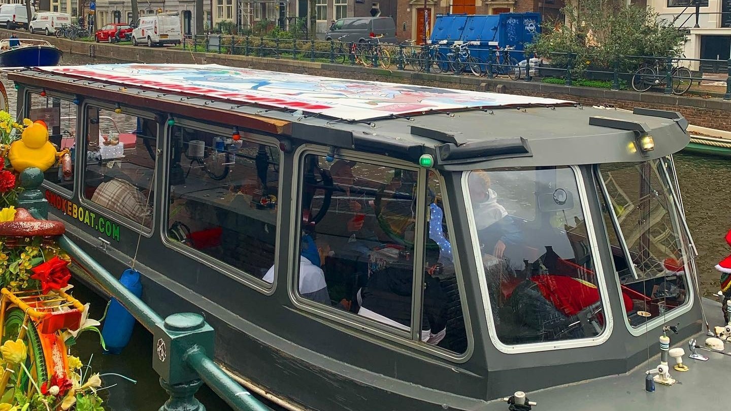 Canal boat moored next to a decorated bicycle in an urban setting.
