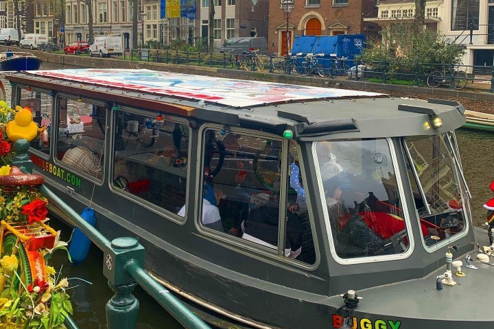 Canal boat moored next to a decorated bicycle in an urban setting.