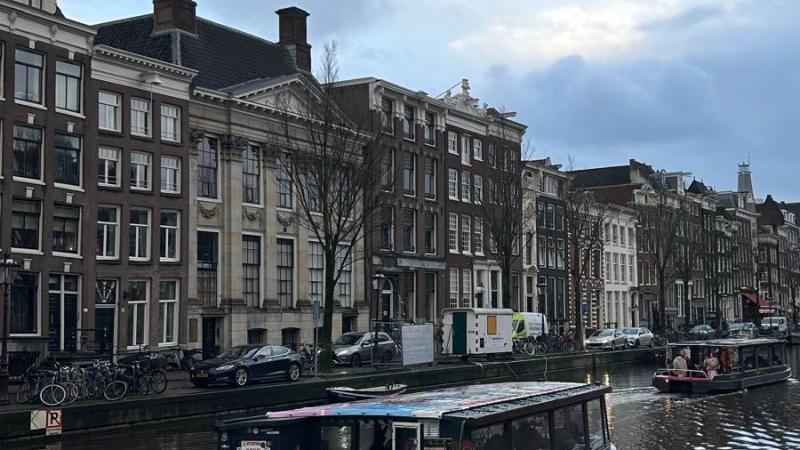 Canal boat cruises on a city canal with historic buildings lining the bank.