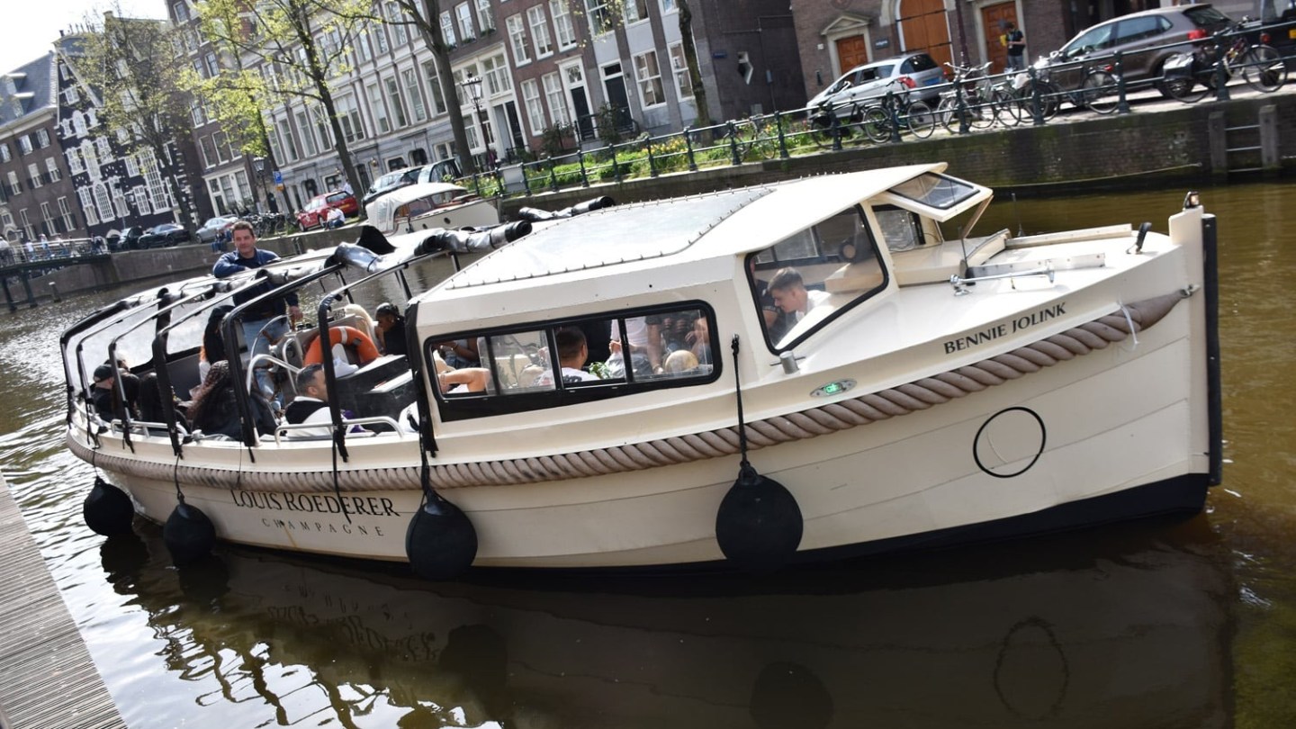 Tour boat navigating a canal in a city with brick buildings.
